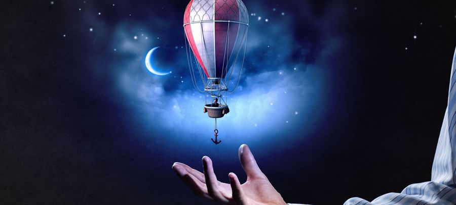 Una ilustraci&oacute;n fant&aacute;stica mostrando una mano masculina extendida hacia un globo aerost&aacute;tico que flota en un espacio celestial oscuro iluminado por las estrellas y una luna creciente.