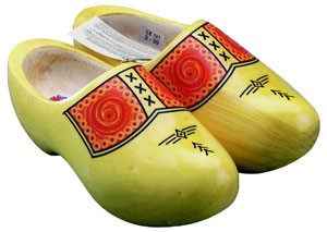 Un par de zuecos de madera tradicionales pintados en amarillo con decoraciones en rojo y detalles geom&eacute;tricos en negro en la parte superior.