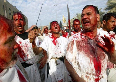 Un grupo de hombres con t&uacute;nicas blancas manchadas de rojo, algunos con las caras cubiertas de la misma sustancia, caminan bajo un cielo despejado. Uno de ellos sostiene una espada hacia el cielo.