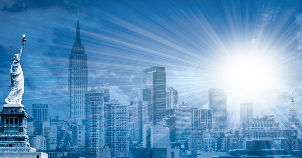 Paisaje urbano con la Estatua de la Libertad y el Edificio Empire State destac&aacute;ndose contra un cielo que irradia rayos de luz solar, evocando la grandeza del firmamento.