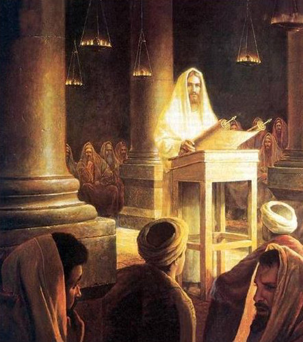 Pintura de una escena b&iacute;blica que muestra a Jes&uacute;s ense&ntilde;ando en una sinagoga. Est&aacute; en el p&uacute;lpito, con una luz brillante a su alrededor, frente a una audiencia atenta de hombres y mujeres en t&uacute;nicas tradicionales. Las columnas y l&aacute;mparas de aceite a&ntilde;aden un ambiente antiguo.