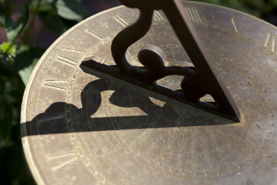 Imagen de un reloj solar de bronce con un gn&oacute;mon proyectando una sombra sobre una superficie circular grabada con n&uacute;meros romanos y s&iacute;mbolos relacionados con el Mazzaroth.