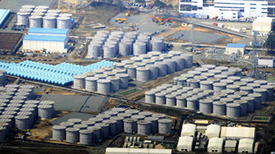 Vista a&eacute;rea de una instalaci&oacute;n industrial con numerosos tanques de almacenamiento grandes y circulares agrupados en filas, rodeados de veh&iacute;culos de construcci&oacute;n y estructuras de soporte en un &aacute;rea extensa.