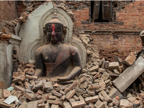 Una estatua de Buda en meditaci&oacute;n, parcialmente cubierta por escombros de ladrillos en un entorno de estructura da&ntilde;ada, simbolizando quiz&aacute;s la durabilidad espiritual frente a la destrucci&oacute;n f&iacute;sica.