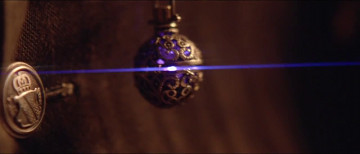 Un colgante esf&eacute;rico y ornamentado suspendido, iluminado por una delgada l&iacute;nea l&aacute;ser azul en un fondo oscuro, reflejando un enfoque en conceptos relacionados con la Mazzaroth en un entorno cient&iacute;fico.