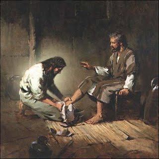 Pintura al &oacute;leo de dos hombres en una escena b&iacute;blica, donde uno lava los pies del otro en una habitaci&oacute;n humilde con suelo de madera y paredes oscuras, evocando humildad y servicio.