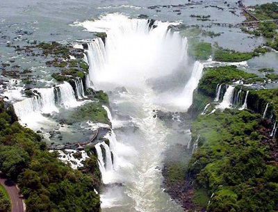 Imagen a&eacute;rea de una gran cascada con m&uacute;ltiples ca&iacute;das de agua rodeadas de exuberante vegetaci&oacute;n verde.