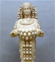 Estatua de marfil de una figura femenina con m&uacute;ltiples esferas y adornos circulares representando las constelaciones mazzaroth. La estatua presenta un peinado detallado y una expresi&oacute;n serena.