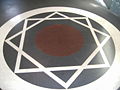 Imagen de un dise&ntilde;o geom&eacute;trico blanco sobre fondo negro, mostrando un hexagrama inscrito en un c&iacute;rculo.